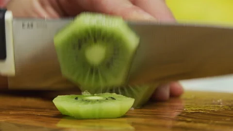 Large knife slicing up shaved kiwi on chopping board in slow motion Stock Footage 341257563