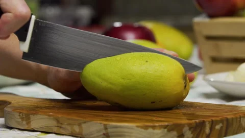 Large knife slicing through delicious mango on all ends - closeup shot Stock Footage 341251957