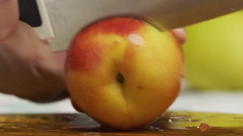 Large knife slicing through fresh peach on chopping board - slow motion Stock Footage 341230953
