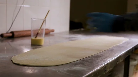 Large layer of dough on the table in the bakery, lubricates with a brush Stock Footage 106468045