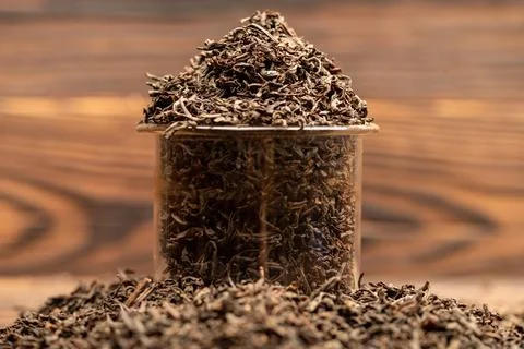 Large-leaf black tea in a glass and scattered on the table. Close-up of the Stock Photos