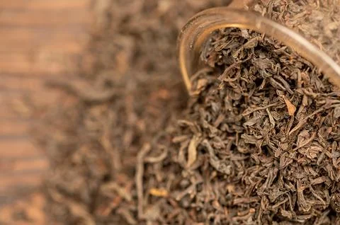 Large-leaf black tea in a glass and scattered on the table. Close-up of the Stock Photos