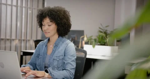 Large leaf moving away revealing African American woman typing on laptop at Stock-Footage 344672569