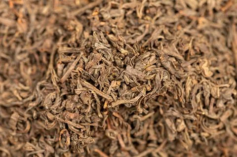 Large-leaved black tea in bulk on the table. Close-up of the surface texture Stock Photos
