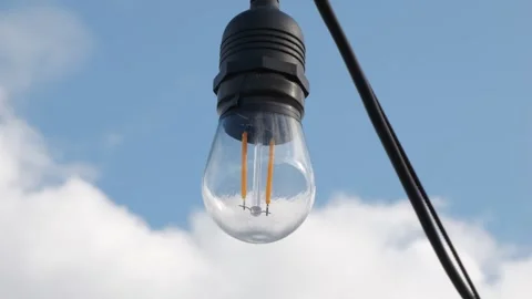 Large LED light bulb swaying against the sky slow motion stock footage 스톡 동영상 332835530
