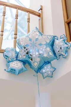 Large light blue foil balloon shaped like a snowflake floating indoors near a 库存照片
