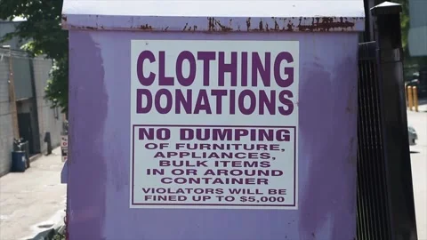 Large light purple metal bin with sign that says clothing donations no dumping Stock Footage 246135236