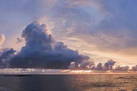 A large lilac dark cloud cloud over a quiet calm sea, a beautiful evening sunset Stock Photos