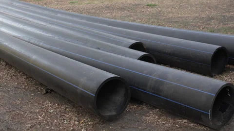 Large long plastic black pipes lie on the ground outside. Stock-Footage 286026773