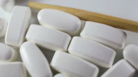 Large long shiny tablets in a shell are moved into the frame with a wooden stick Stock Footage 144643526