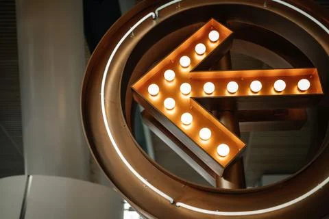 A large luminous arrow decorated with light bulbs in the background Stock Photos