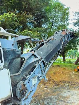 A large machine is actively cutting and removing trees in a park. The equipme Fotos de archivo