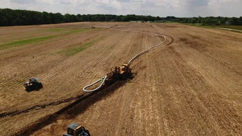 Large machine expertly lays pipes in a sprawling field. Stock Footage 259326154