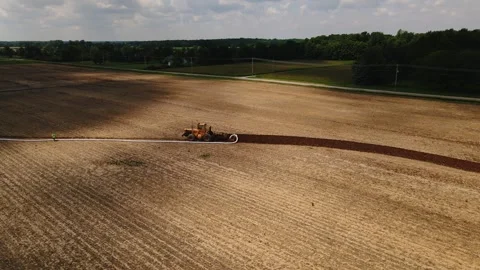 Large machine expertly lays pipes in a sprawling field. Stock Footage 259326160