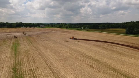 Large machine expertly lays pipes in a sprawling field. Stock Footage 259326405