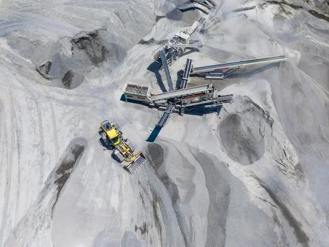 A large machine works in the granite quarry, moving and processing stones. Ot Stockfoto's