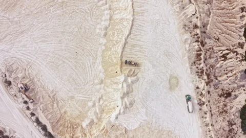 Large machinery works on a salt mining site with spread mounds of processed salt Stock Footage 345456361