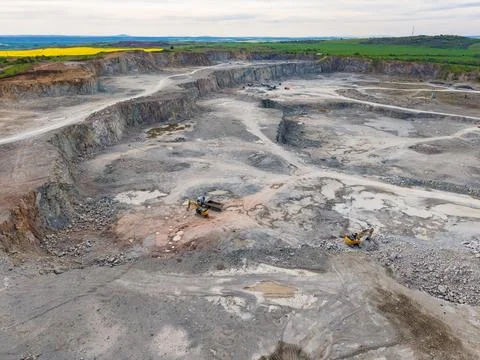 Large machines operate in a mining site, moving earth and rock. The scene sho Stockfoto's