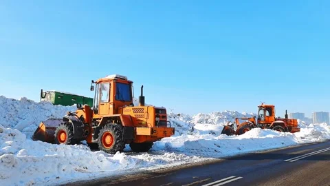 Large machines remove snow from the roads in a city during winter on a clear day Stock Footage 328487469