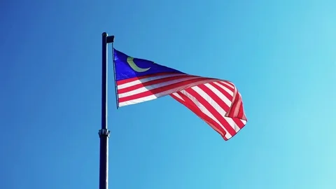 A large Malaysian flag waving at the wind with blue clear sky at the background Stock Footage 84575932