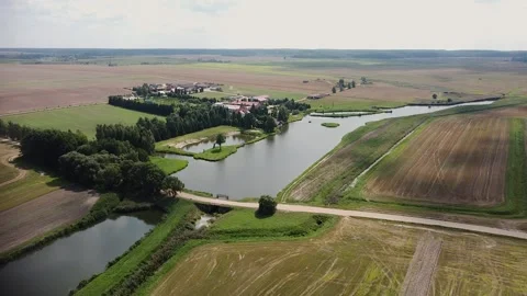 A large manor in a field with green grass near a river. A farm in a field with g Stock Footage 323132268