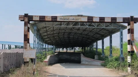 Large metal corrugated roofing structure over a paved rural road Видео 329561177