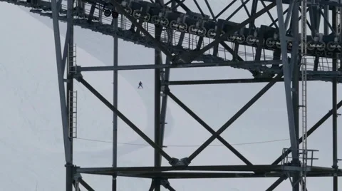 Large metal pillars passing beneath a cable car on top of slopes that descend Stock Footage 68935534