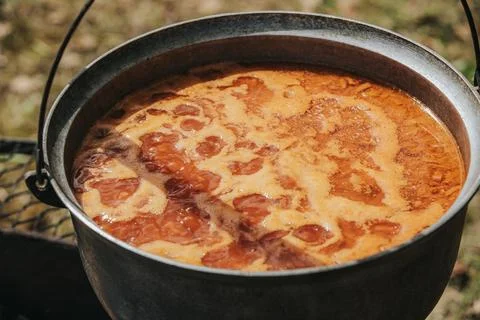 Large metal pot filled with boiling brown liquid, bubbles forming on the su.. Stock Photos