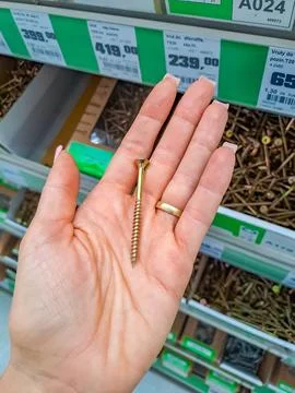 Large metal screws with a hexagonal hat in the girl's hand. Stock Photos