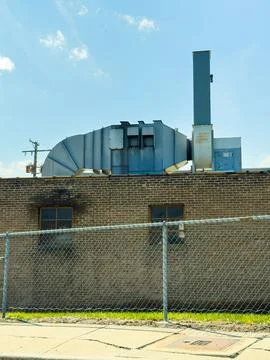 A large metal ventilation system is situated on the roof of a brick building. 스톡 사진