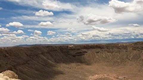 A large meteor crater under a blue sky filled with puffy white clouds-41 Stock Footage 346411319