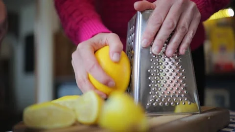 Large Meyer lemon is shredded on kitchen grater to get citrus peel zest Stock Footage 336219514