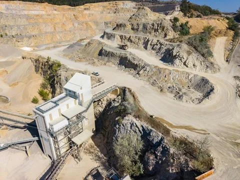 A large mining operation takes place in a quarry filled with machinery and he Stock Photos