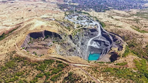 Large mining pit with water at the bottom located in a dry landscape under a Stock Footage 343553770