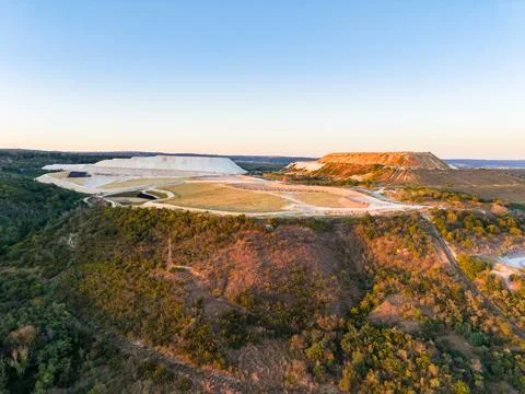 Large mining site near a forest area at sunset showing earth movement and s.. Stock Photos