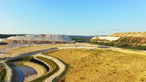 Large mining site shows extraction process and surrounding area under clear blue Stock Footage 341029755