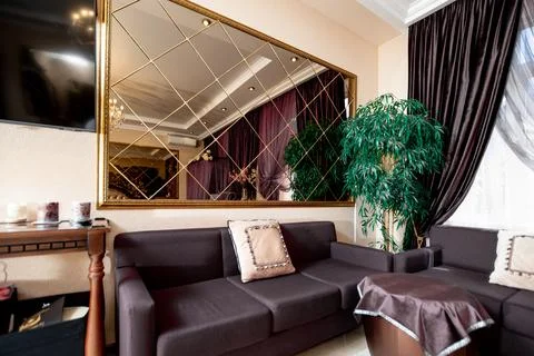A large mirror hangs on the wall above a couch Stock Photos