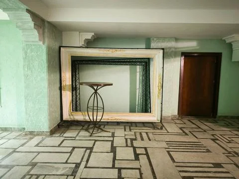 A large mirror is on a table in a room with a green wall. Stock Photos