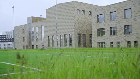 Large modern school building with tan brick facade Видео 334683746