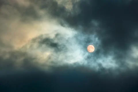 A large moon in a cloudy sky with thick clouds. Full moon. The night sky with Stock Photos