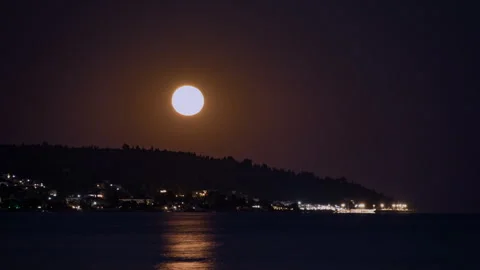 Large moon hangs above dark Aegean sea in Greece Vídeos de archivo 346245419