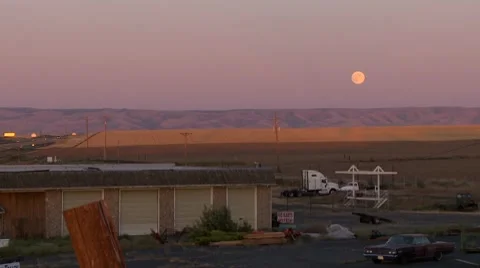 Large moon rises over colorful hills Stock Footage 8677534