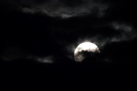 A large moon is visible in the sky, surrounded by dark clouds Stock Photos