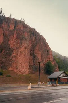 Large mountain beside a structure along a paved highway in a foggy area. Stock Photos