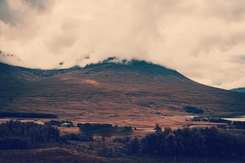 Large mountain with its summit hidden in thick cloud above brown moorland 库存照片