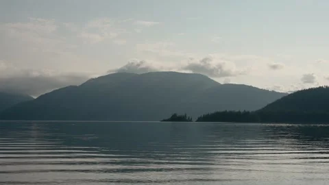 Large mountain lake clouds sun rays sunset lush coniferous tree forest islan Stockbeeldmateriaal 277669171