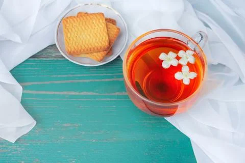 A large mug of tea with fallen white jasmine flowers on a white airy backgrou Photos