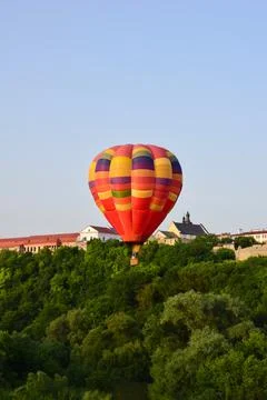 A large multi-colored balloon flies very low over the river and between trees Stock Photos