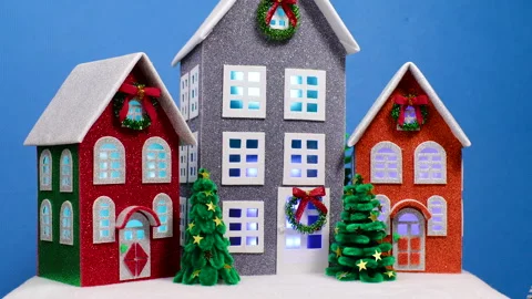 Large multi-colored houses surrounded by small Christmas trees rotate Stock Footage 322049305
