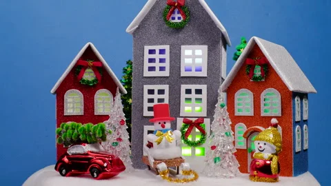 Large multi-colored houses surrounded by small Christmas trees and a snowman Stock Footage 322049470
